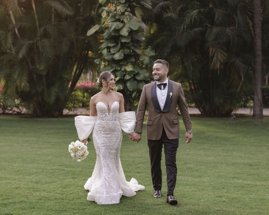 Novios caminando de la mano por un jardín