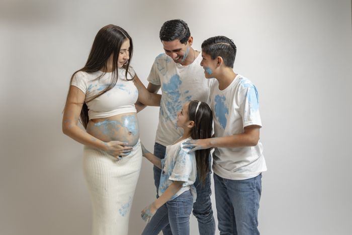 Familia con huellas de pintura azul sobre el vientre de la mamá