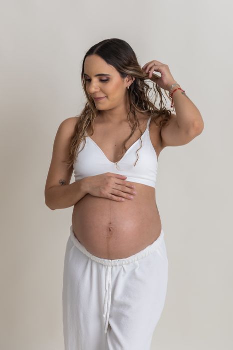 Futura mamá sola, con top blanco, tocándose el vientre