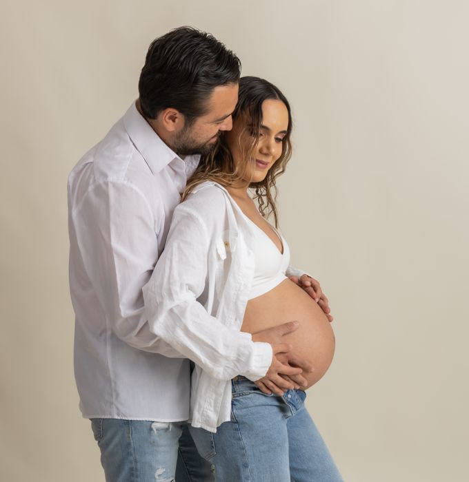 Pareja esperando bebé, él abrazándola por detrás